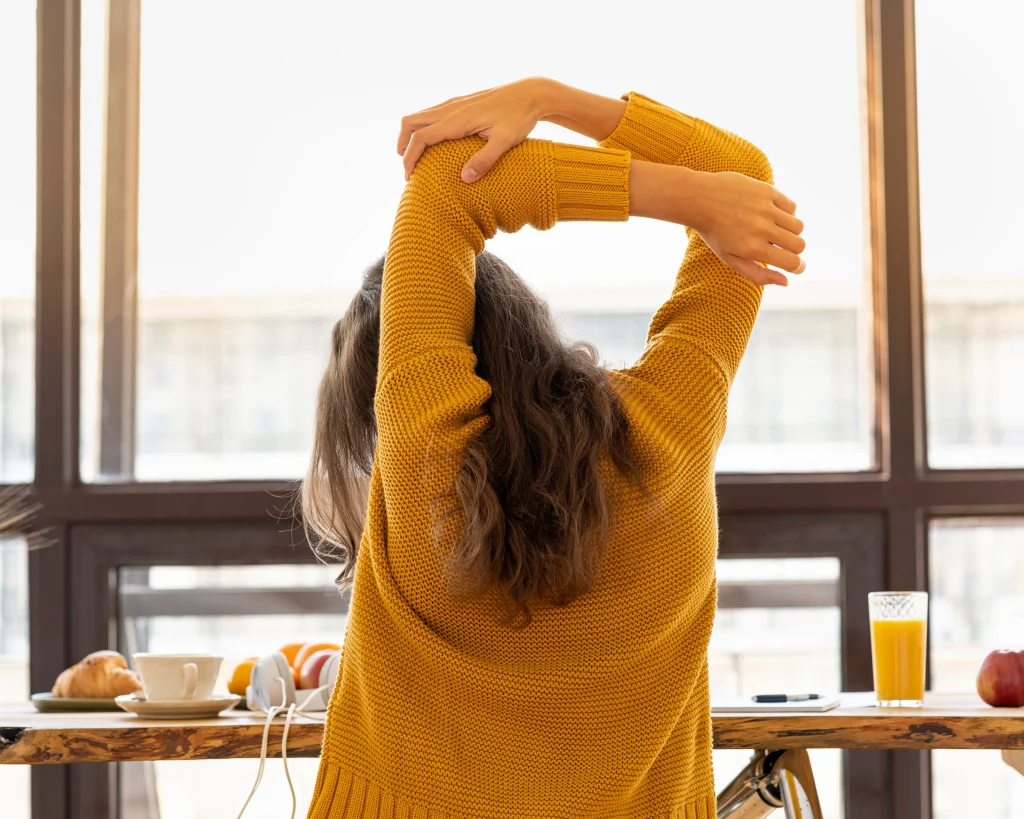 Woman stretching back while sitting at desk